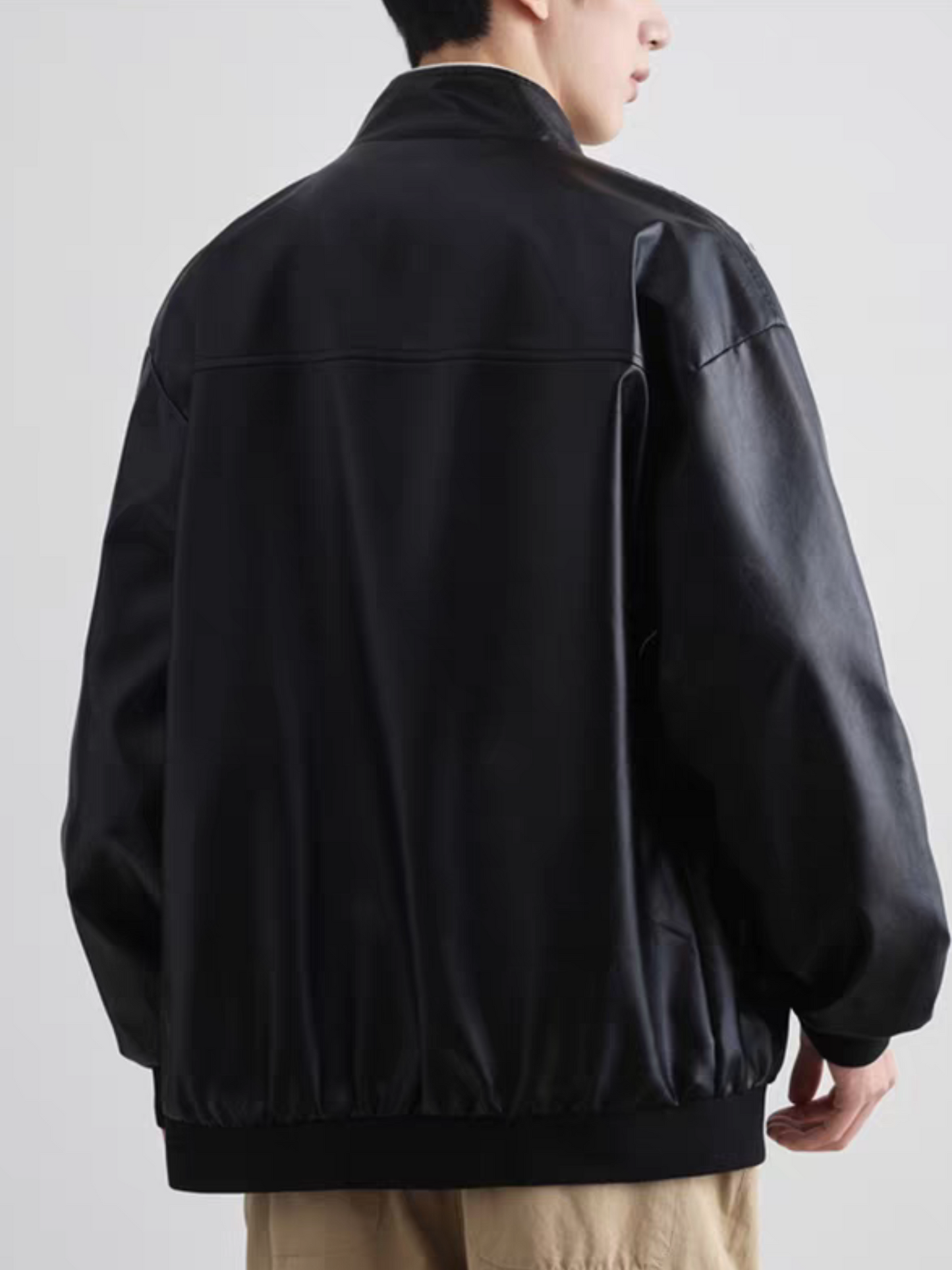 Back view of Black PU leather racing jacket with clean and minimal design, worn by male model