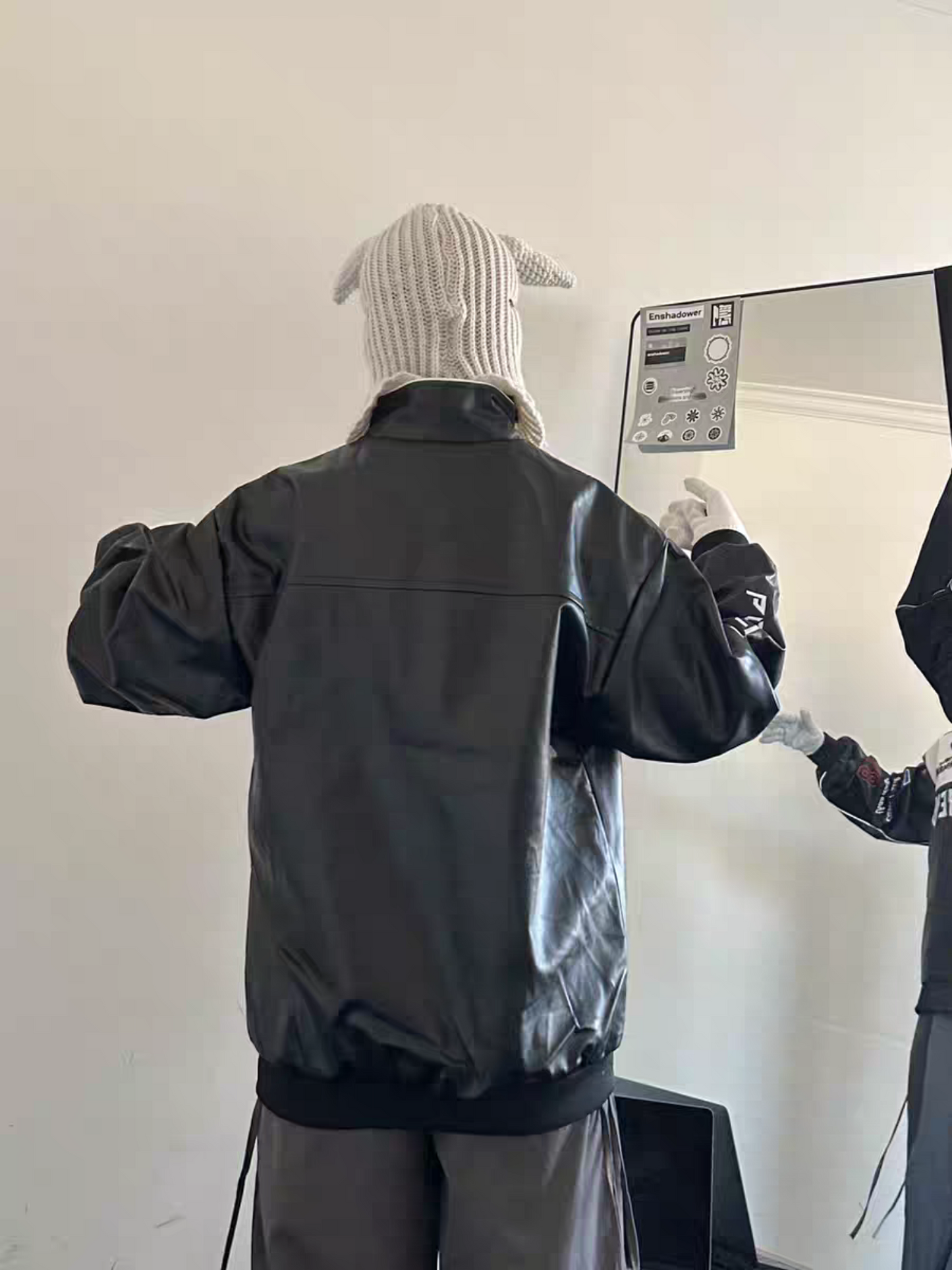 Back view of male model wearing black racing PU leather jacket, showcasing smooth texture and relaxed fit