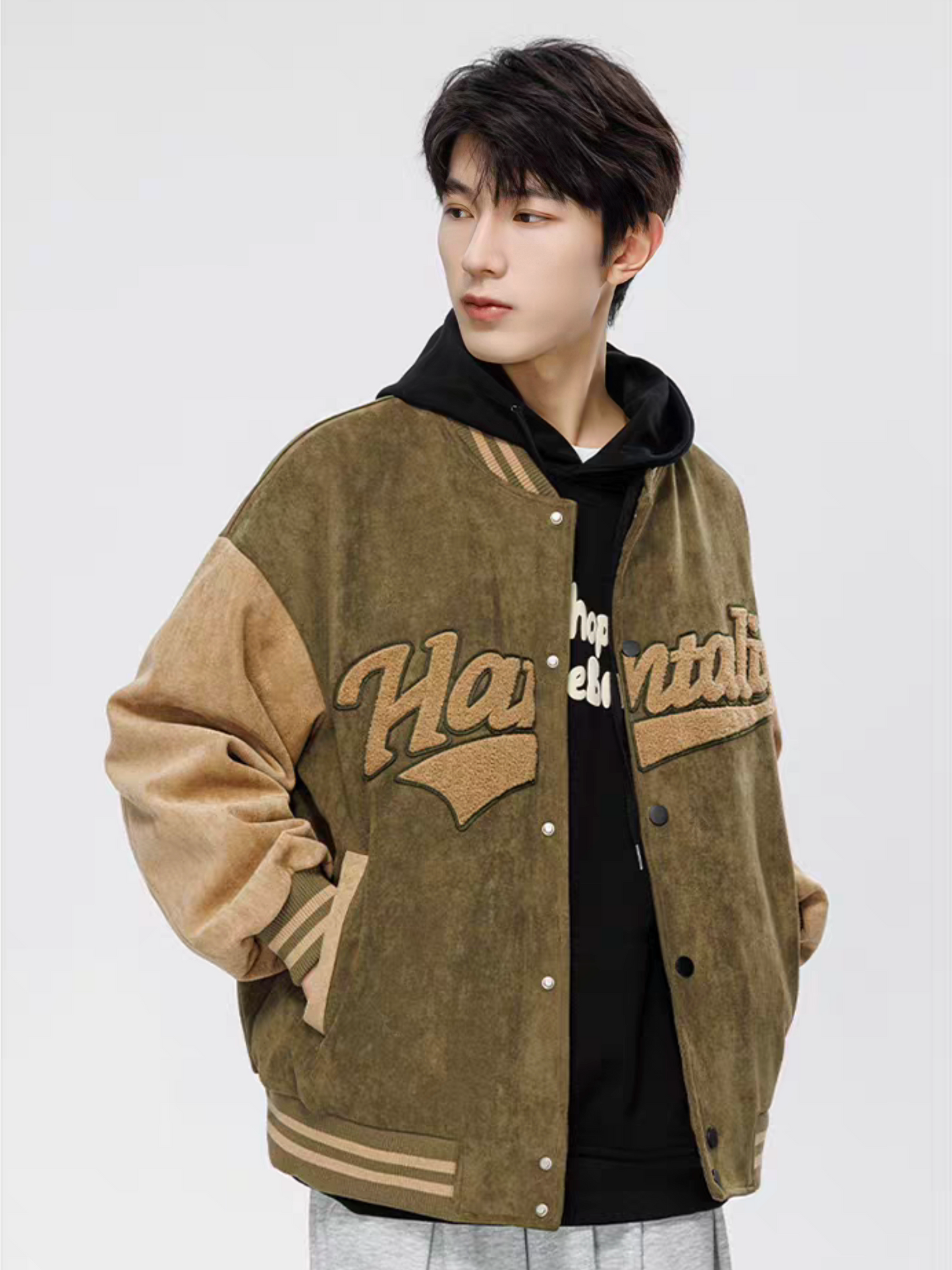 Side view of male model wearing green and brown varsity jacket with chenille ''Hantaliv'' lettering and striped cuffs