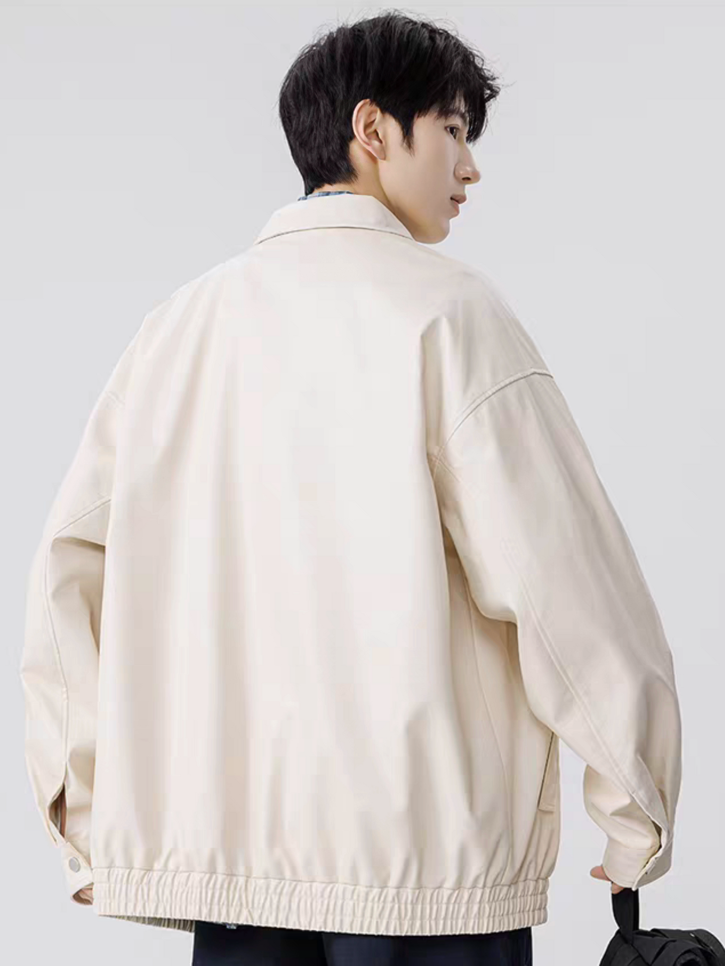 Male model in white faux leather PU jacket, back view with head turned sideways, minimal clean background, showcasing Korean casual fashion