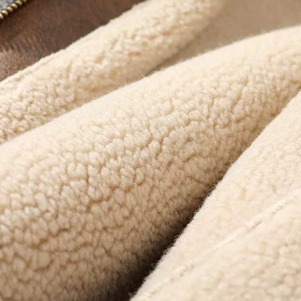 Close-up of soft beige faux shearling lining inside brown aviator jacket, showing plush texture