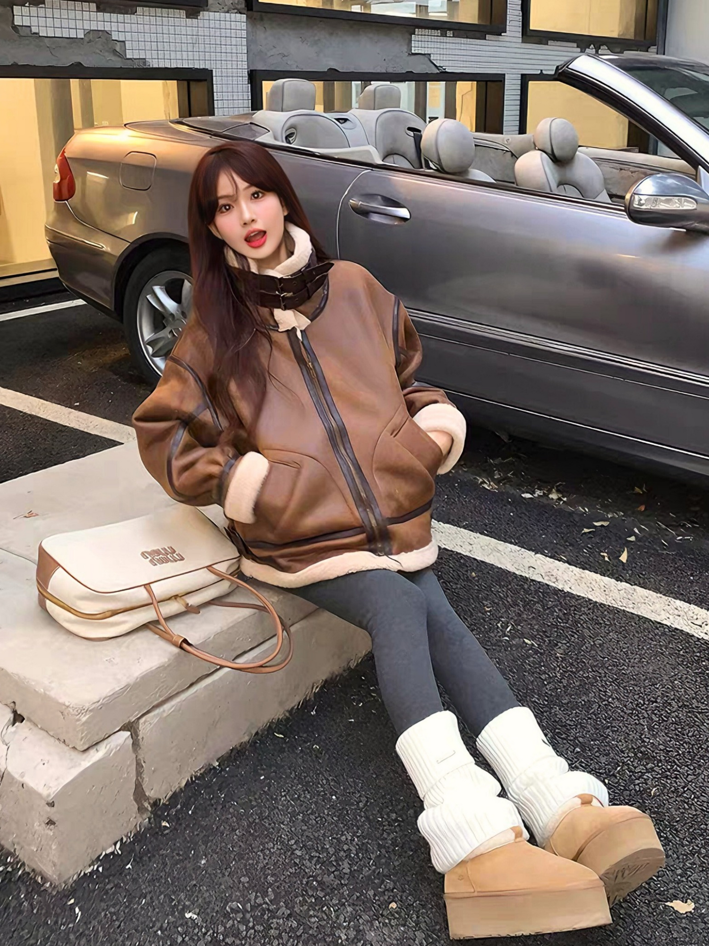 Woman in brown faux shearling aviator jacket sitting beside convertible car, wearing cozy winter outfit