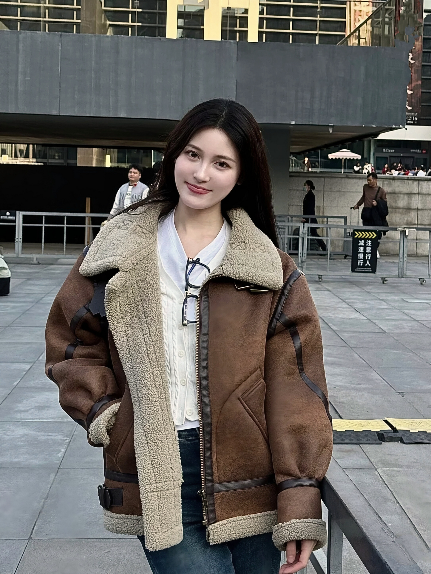 Smiling woman wearing brown faux shearling aviator jacket in casual city street style