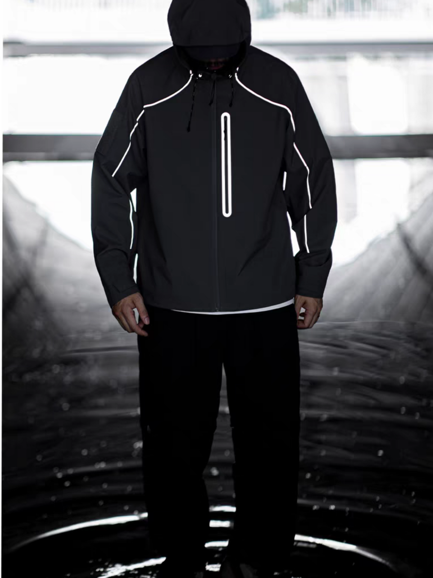 Hooded model showcasing STVLE lightsaber reflective jcaket in front view, standing in a water-themed sci-fi backdrop