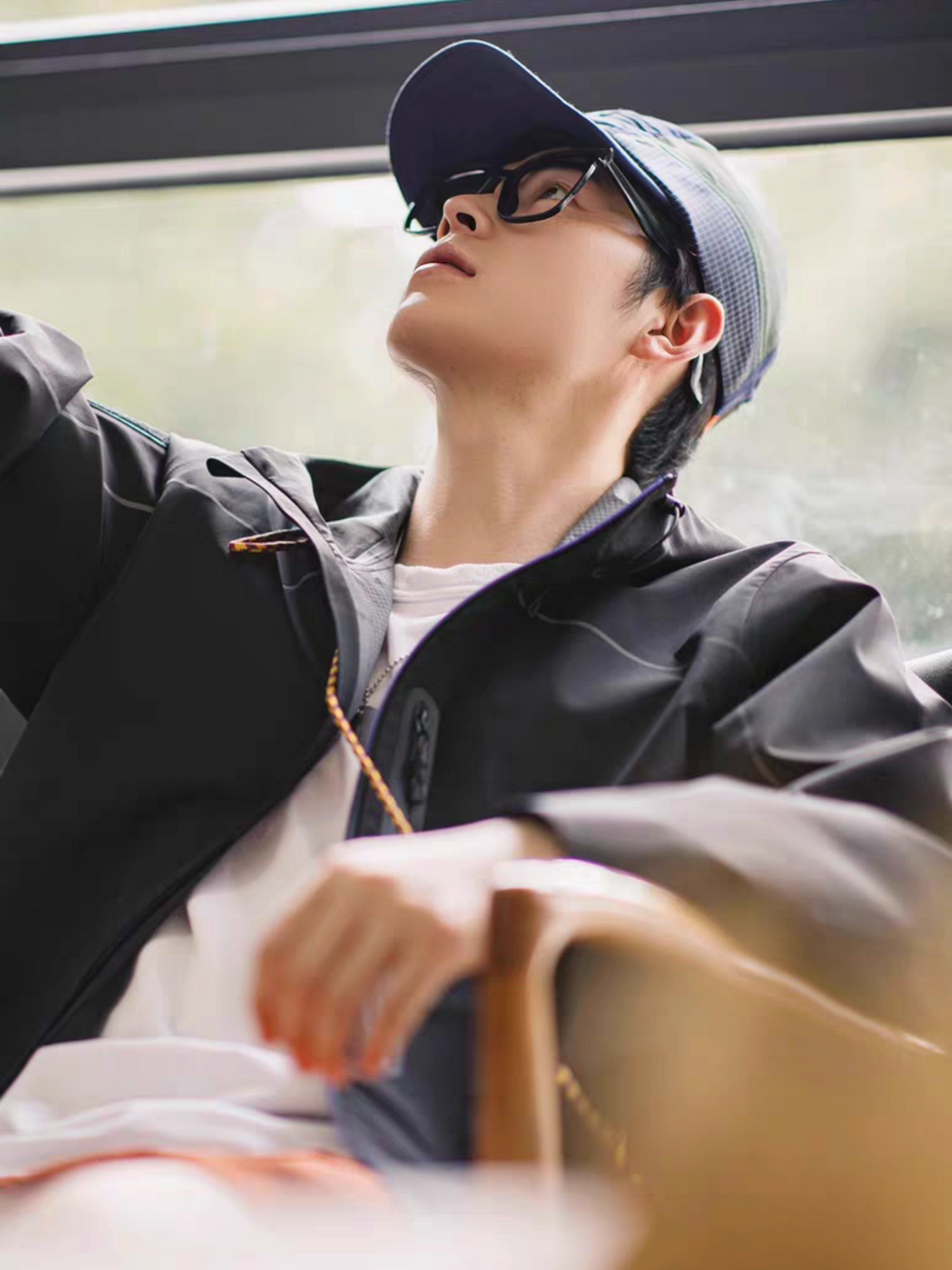 Male model lounging indoors in STVLE lightsaber techwear jacket, casual and stylish streetwear look