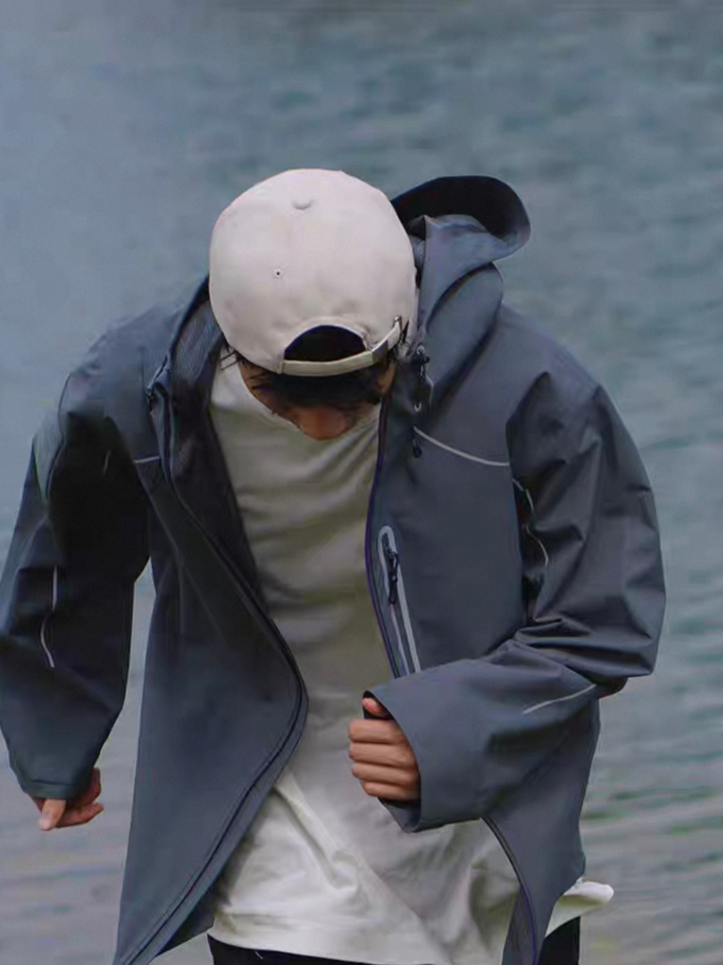 Model wearing STVLE lightsaber techwear jacket walking outdoors by the lake, showing windproof and water-resistant design in natural movement
