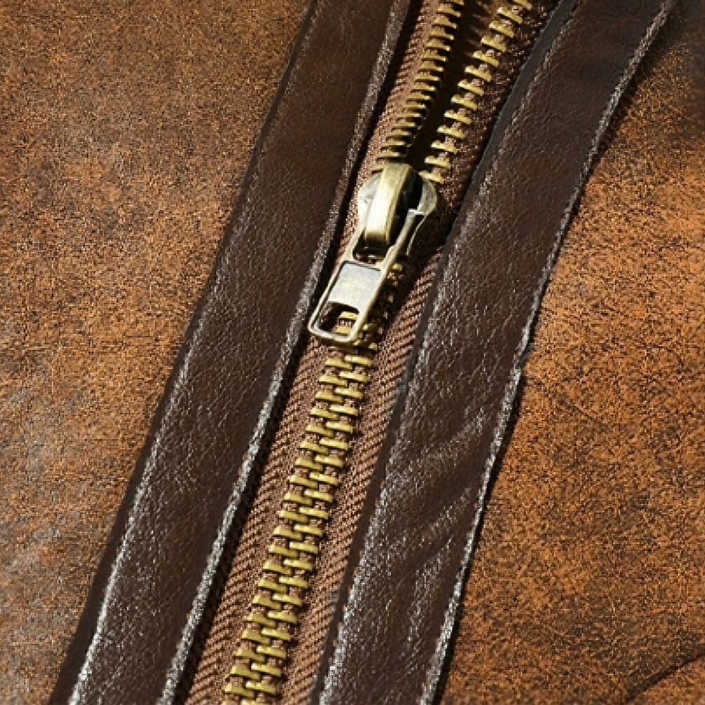 Close-up of brass zipper with leather trim on brown faux shearling aviator jacket